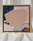 Framed abstract art piece with 'MORE' text on a neutral background