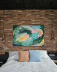 Abstract painting on a brick wall above a bed with colorful pillows.